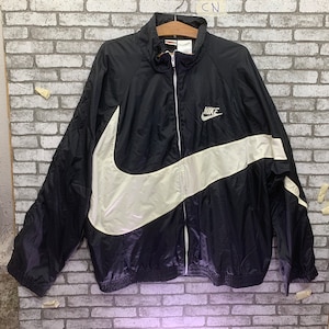May include: Black windbreaker jacket with a large white Nike swoosh and the word "NIKE" in white lettering.