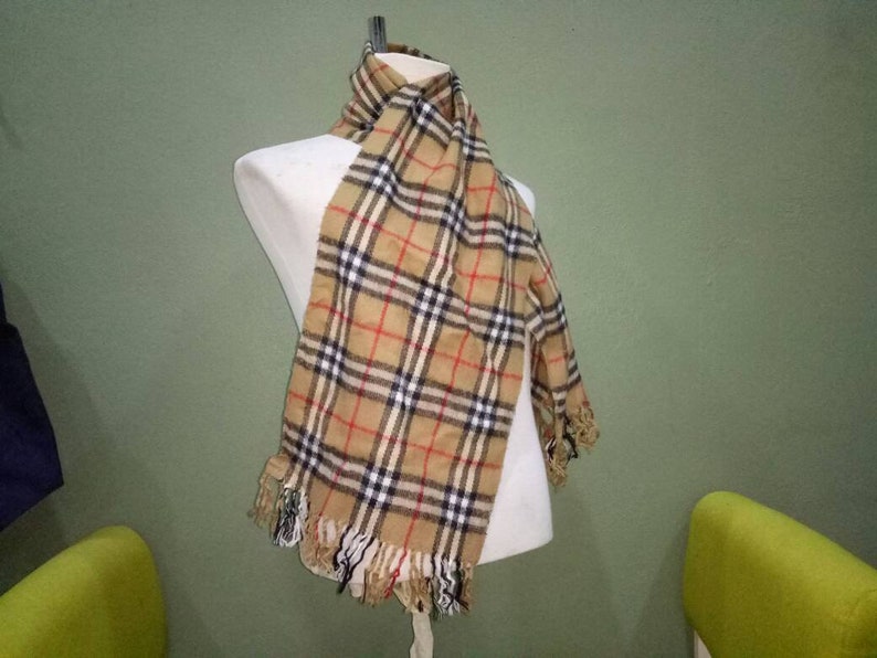 May include: A brown and beige plaid scarf with black and red accents. The scarf has fringe on the ends.