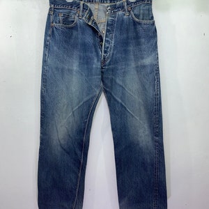 May include: A pair of blue denim jeans with a button fly and a faded look.