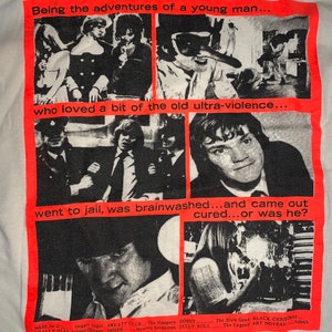 May include: A white t-shirt with a red graphic print of a collage of black and white images. The text on the graphic reads "Being the adventures of a young man... who loved a bit of the old ultra-violence... went to jail, was brainwashed...and came out cured...or was he?"  The bottom of the graphic lists the names of movies and directors.