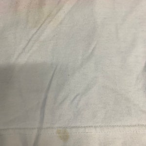 May include: A white t-shirt with a few small stains. The shirt is made of a soft, comfortable material.