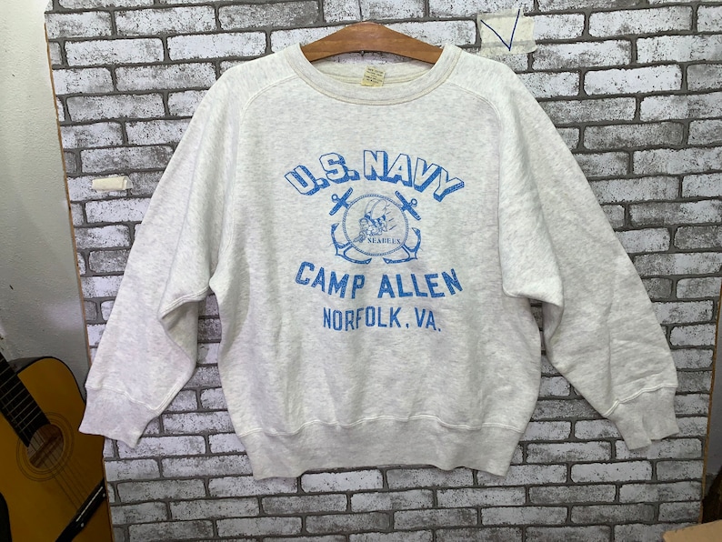 May include: A gray sweatshirt with a blue graphic print of a navy anchor and the text "U.S. Navy Camp Allen Norfolk, VA."
