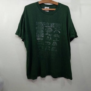 May include: A dark green t-shirt with a faded print of the text "Showcase Theatre" and a list of bands including "That Guy", "Dillinger Four", and "The Suicide Machines".