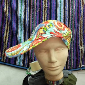 Könnte beinhalten: Eine bunte Baseballkappe mit Paisley-Muster in Blautönen, Rot, Gelb und Grün. Die Kappe hat ein gebogenes Visier und eine weiße Krone.