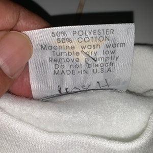 Pu&ograve; includere: Etichetta di cura bianca con testo nero che recita: "50% Poliestere 50% Cotone Lavaggio in lavatrice a caldo Asciugatura in asciugatrice a bassa temperatura Rimuovere tempestivamente Non candeggiare Prodotto negli Stati Uniti"