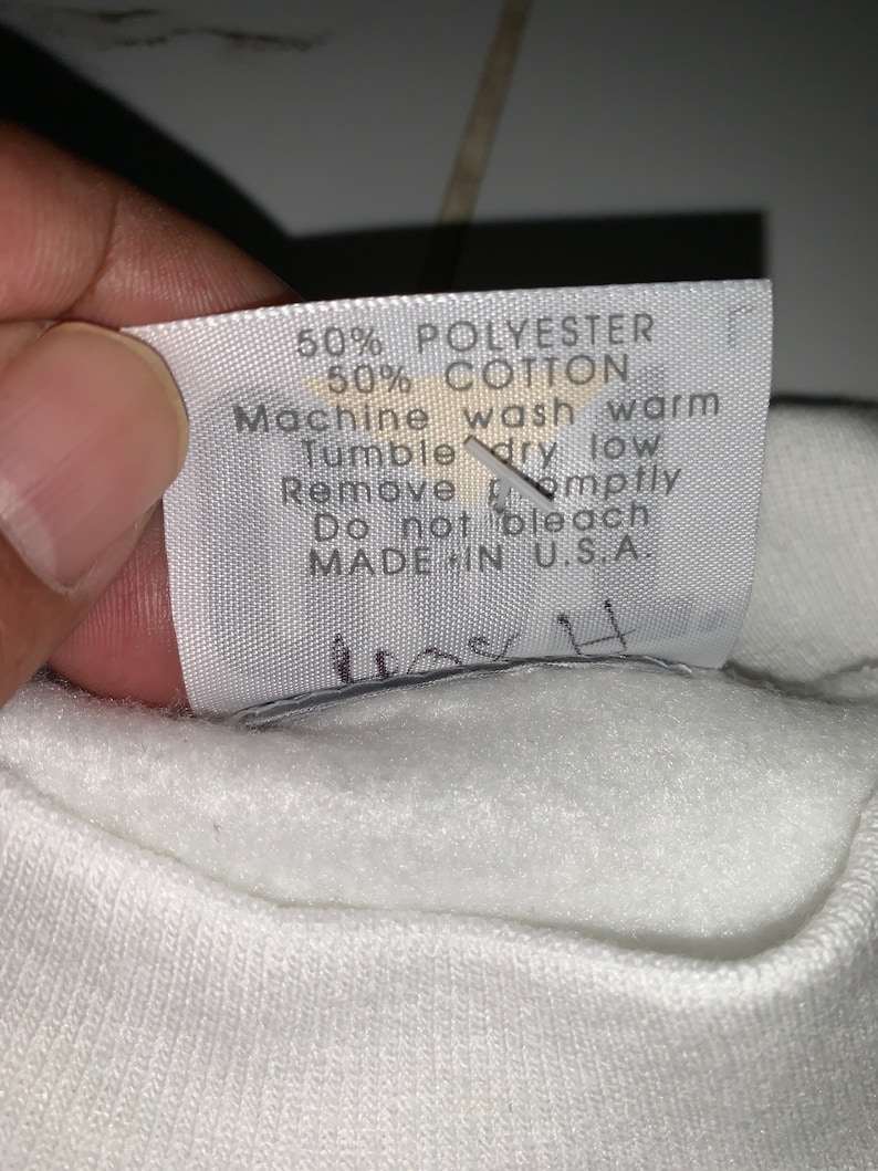 Pu&ograve; includere: Etichetta di cura bianca con testo nero che recita: "50% Poliestere 50% Cotone Lavaggio in lavatrice a caldo Asciugatura in asciugatrice a bassa temperatura Rimuovere tempestivamente Non candeggiare Prodotto negli Stati Uniti"