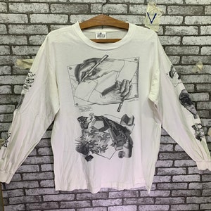 May include: White long-sleeve t-shirt with a black and white graphic print of a person drawing. The graphic includes the text "Mr. Escher - 1900 - 1972".