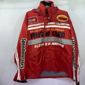 May include: A red and black racing jacket with a hood. The jacket features reflective stripes, the text "YELLOW CORN", "Speedmasters", and other racing-themed graphics. The jacket is designed for motor sports.