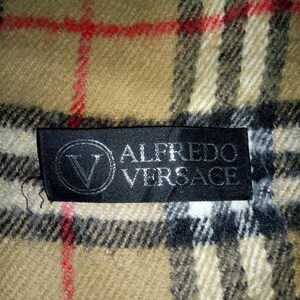 May include: A black and white plaid scarf with a black label that reads "Alfredo Versace".