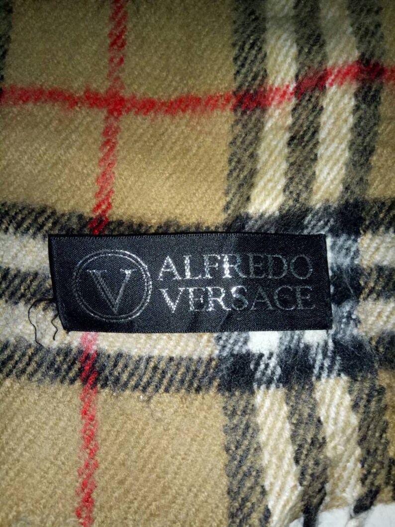 May include: A black and white plaid scarf with a black label that reads "Alfredo Versace".