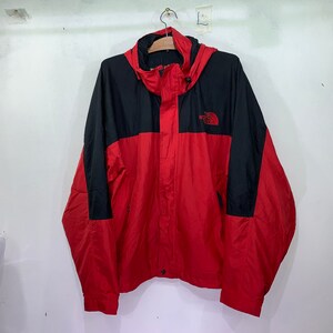 May include: A red and black hooded jacket with a zipper closure and the North Face logo on the chest.