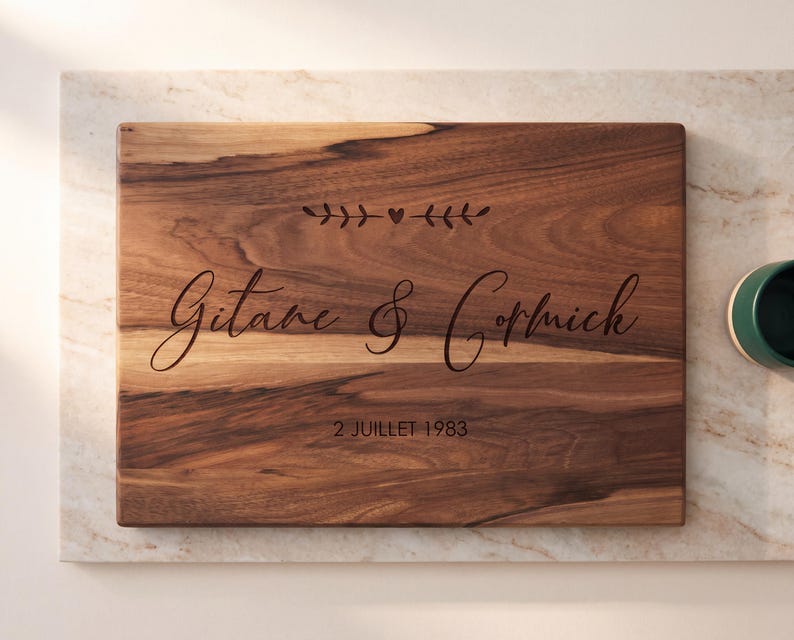 A wooden cutting board with the names "Guitare & Corniche" engraved on it, along with the date "2 JULET 1983".