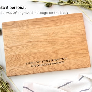 a wooden cutting board with a message engraved on it, surrounded by some greenery and a white cloth.