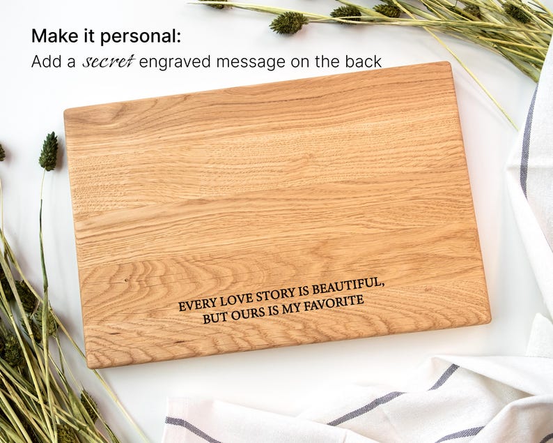 a wooden cutting board with a message engraved on it, surrounded by some greenery and a white cloth.