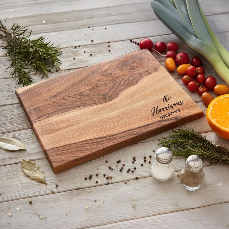 A wooden cutting board with a personalized inscription, surrounded by various fresh fruits, herbs, and spices on a wooden surface.