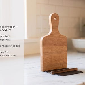 a wooden cutting board with a black handle, placed on a white countertop.
