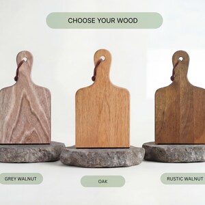Three wooden cutting boards, each with a different color and finish, are displayed against a white background.