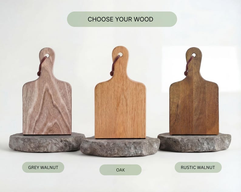 Three wooden cutting boards, each with a different color and finish, are displayed against a white background.