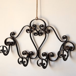 Può includere: Un appendiabiti da parete in ferro battuto nero con un design decorativo a volute e sei ganci.