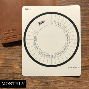 May include: A white circular calendar with a black border and numbers for the month of June. The text "June" is written in cursive at the top of the calendar.
