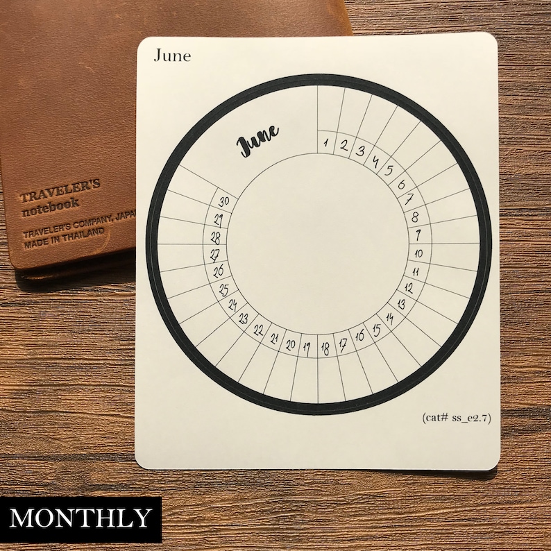 May include: A white circular calendar with a black border and numbers for the month of June. The text "June" is written in cursive at the top of the calendar.