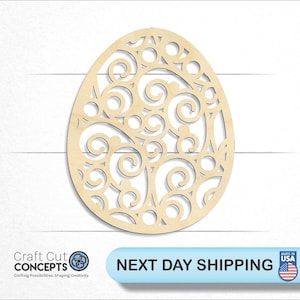 May include: A wooden cutout of an egg with a decorative, intricate swirl pattern. The egg is light brown and has a smooth, unfinished surface.