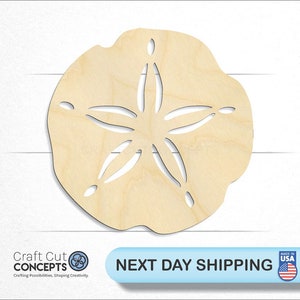 May include: A wooden cutout of a sand dollar with a five-pointed star design. The cutout is light brown and has a smooth, unfinished surface.