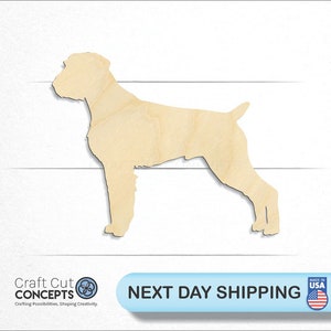 May include: A wooden cutout of a dog in a standing position. The dog is facing to the right. The cutout is made of light brown wood.