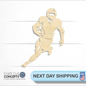 May include: Wooden cutout of a football player running with the ball. The player is wearing a helmet and uniform. The cutout is beige in color.