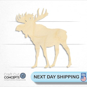 May include: A wooden cutout of a moose in a standing position. The moose is light brown and has large antlers. The cutout is made of unfinished wood.