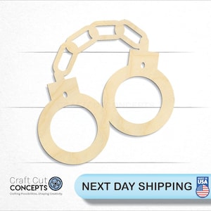 May include: A wooden cutout of handcuffs, connected by a chain. The handcuffs are light brown and have circular openings. The image is on a white background with the text "Craft Cut Concepts" and "Next Day Shipping".