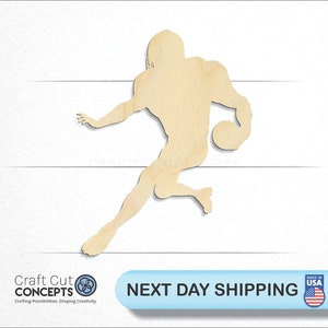 May include: Wooden cutout of a football player in a running pose, holding a football. The cutout is unpainted and made of natural wood.