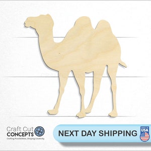 May include: A wooden cutout of a camel, standing on all four legs. The camel is light brown and has a hump on its back. The cutout is made of unfinished wood.