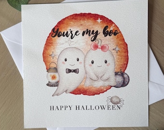 Op de afbeelding: Vierkante Halloween-wenskaart met de tekst "You're my boo" boven twee cartoongeesten. Eén geest heeft een vlinderdas en de andere een strik. De kaart zegt ook "HAPPY HALLOWEEN" met een spin eronder.