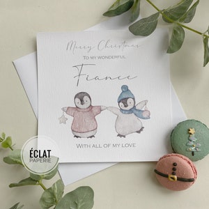 May include: A Christmas card with two penguins wearing hats and scarves. The card says "Merry Christmas to my wonderful fiance with all of my love".