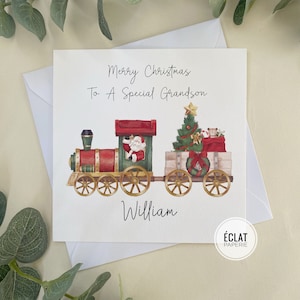 May include: A Christmas card with a red and green train carrying a Christmas tree and presents. The card says "Merry Christmas To A Special Grandson" and is signed "William".