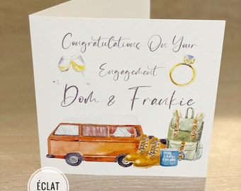 May include: A white card with a handwritten message that says "Congratulations on your engagement,  Dom & Frankie". The card has a watercolor illustration of a vintage camper van, two hiking boots, a backpack, a mug that says "Let's Explore", and two champagne glasses.