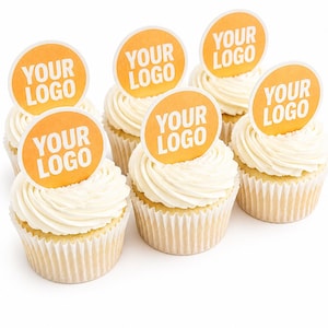 Pode incluir: Seis cupcakes com cobertura branca e coberturas redondas laranja. Cada cobertura tem as palavras "YOUR LOGO" em branco. Os cupcakes estão em formas de papel brancas, sobre um fundo branco.