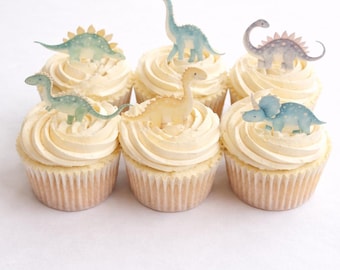 Può includere: Sei cupcake con glassa alla vaniglia, ognuno decorato con un dinosauro diverso. I dinosauri sono in tonalità di blu, verde e giallo. I cupcake sono in pirottini di carta.