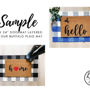 May include: Two doormats with black lettering on a brown coir background. The first doormat says "oh, hello" and the second doormat says "home" with a red heart. Both doormats are layered on top of a black and white buffalo plaid rug.