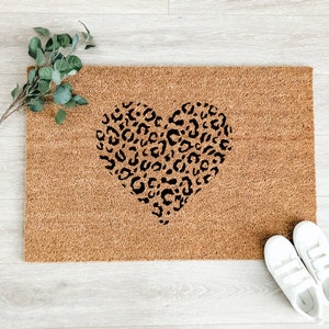 May include: A brown coir doormat with a black leopard print heart design.