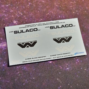 May include: Waterslide decals for a model of the U.S.S. Sulaco spacecraft from the film Aliens. The decals include the ship's name, the Weyland-Yutani Corporation logo, and the words "Aliens: Black Registry" and "Aliens: White Registry".