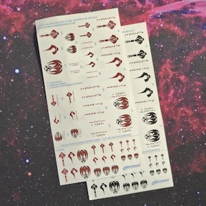 May include: Two sheets of waterslide decals for model building. The decals feature black and red designs of a spaceship with the text "Cardassian", "Obsidian Order", "Klingon/Cardassian Alliance", and "Leeks on Pluto".