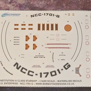 May include: Waterslide decals for a 1:1400 scale model of the USS Enterprise NCC-1701-G starship. The decals include the ship's registration number, the name "Enterprise", and various other details. The decals are printed on clear film and are designed to be cut out and applied to the model.