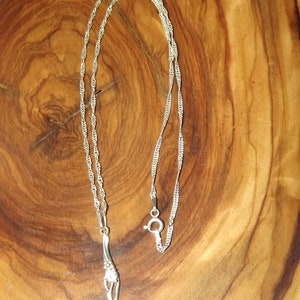 Peut inclure: Un collier en argent avec un pendentif en argent en forme de fleur stylis&eacute;e.