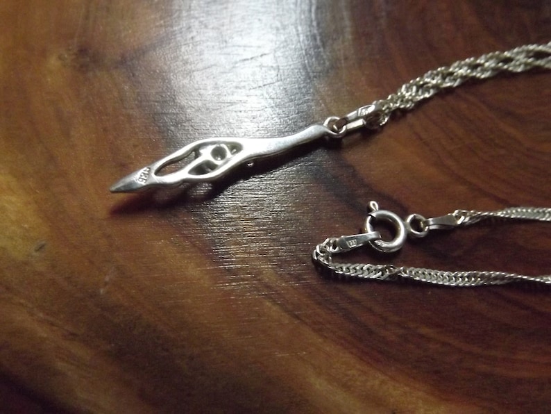 Peut inclure: Un collier en argent avec un pendentif d&eacute;licat et complexe. Le pendentif est en forme d'oiseau stylis&eacute; avec un motif circulaire au centre. La cha&icirc;ne est de style corde torsad&eacute;e.