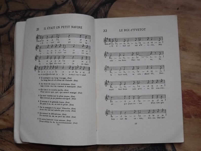 May include: A vintage book with a black and white cover featuring musical notes and lyrics for the French songs "Il &eacute;tait un petit navire" and "Le Roi d'Yvetot".