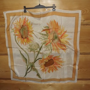 May include: A white silk scarf with a yellow, orange, and green sunflower design.
