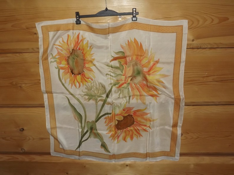 May include: A white silk scarf with a yellow, orange, and green sunflower design.