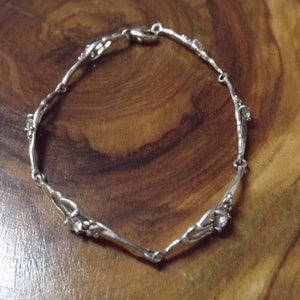 Peut inclure: Un bracelet en argent avec un design d&eacute;licat et torsad&eacute; et de petites pierres claires. Le bracelet a une fermeture &agrave; fermoir.